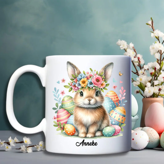 Witte keramische paasbeker met illustratie van haasjes tussen kleurrijke bloemen en optie voor personalisatie met naam - Debekershop.nl