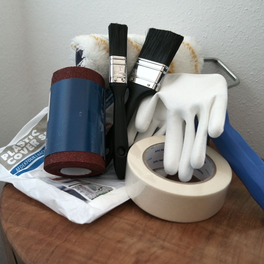 Schilderemmer gevuld: de inhoud met kwasten, handschoenen, afplaktape, schuurpapier en afdekfolie