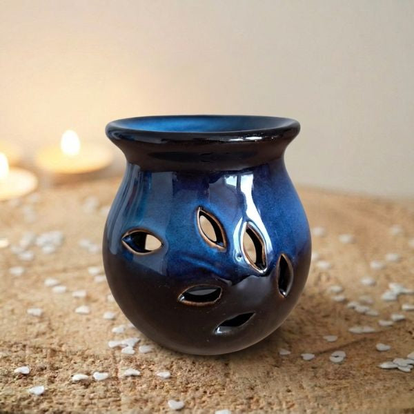 Diepblauwe keramische waxmeltbrander Midnight Ocean met uitgesneden bladvormen, naast brandende theelichtjes, FlexMade