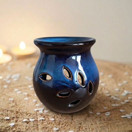 Diepblauwe keramische waxmeltbrander Midnight Ocean met uitgesneden bladvormen, naast brandende theelichtjes, FlexMade